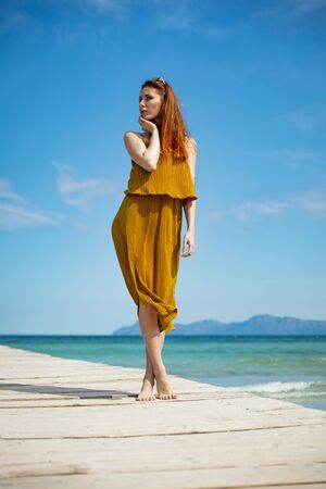 red haired woman at ocean pier in sunny weatherの写真素材