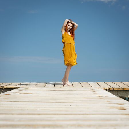 red haired woman at ocean pier in sunny weatherの写真素材