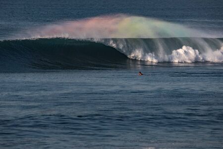 Man surfer swims towards the perfect wave. one of the most beautiful waves on the planet. the wave is smooth as a mirror.rainbow spray from the wave flies in different directions. surfing alone.Paddleの写真素材