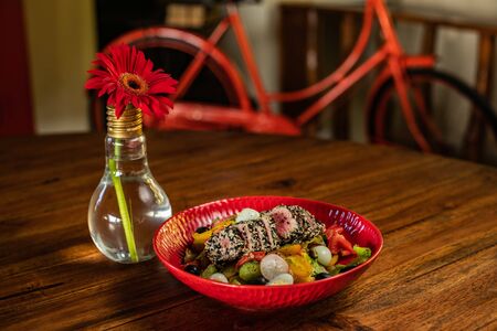 A red plate with food on top of a wooden tableの写真素材