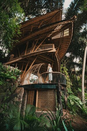 Blonde on balcony of a bamboo house in the jungleの写真素材
