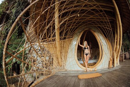 Blonde on balcony of a bamboo house in the jungleの写真素材