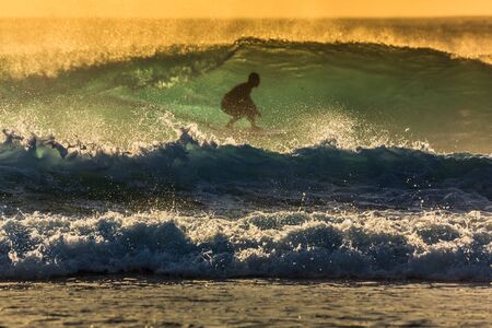 A man riding a barrel wave on a surfboard in the oceanの写真素材
