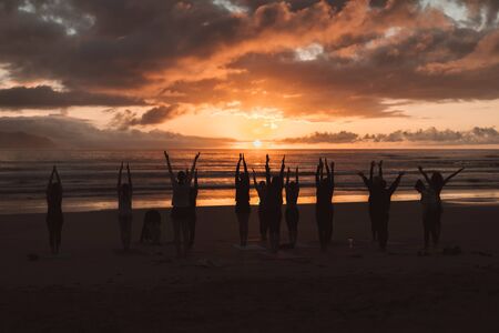 People doing yoga sunsetの写真素材