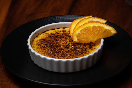 Creme brulee, burnt cream with orange on the dark wood table.の写真素材