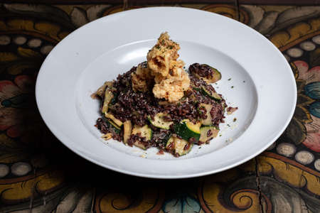 Traditional Spanish seafood paella on a dark wooden table with white wine Veganの写真素材