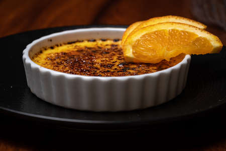 Creme brulee, burnt cream with orange on the dark wood table.の写真素材