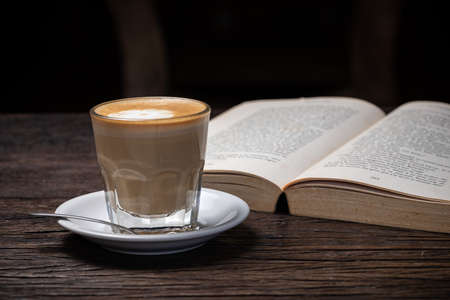 Coffee cup cappuccino hot latte or coffee with milk in a glass cup, open bookの写真素材