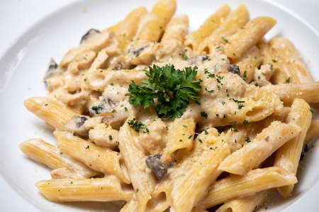 Penne pasta with white mushrooms porcini in creamy sauce on the dark wood tableの写真素材
