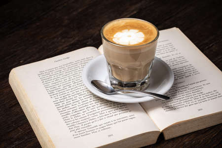 Coffee cup cappuccino hot latte or coffee with milk in a glass cup, open bookの写真素材