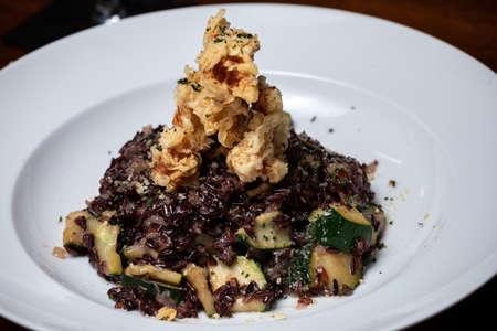 Traditional Spanish seafood paella on a dark wooden table with white wine Veganの写真素材