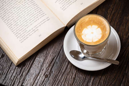 Coffee cup cappuccino hot latte or coffee with milk in a glass cup, open bookの写真素材