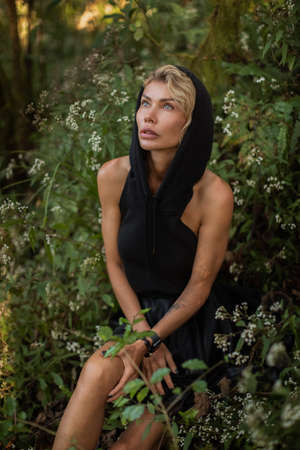 Blonde in black hood dress, white hair in the woods fashion fantasy magicalの写真素材
