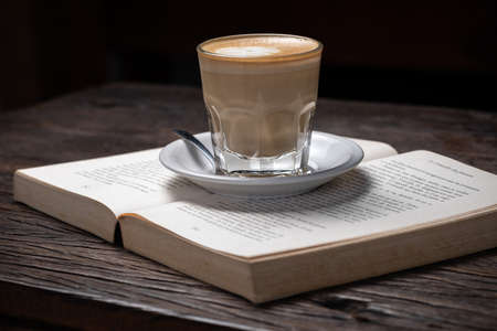 Coffee cup cappuccino hot latte or coffee with milk in a glass cup, open bookの写真素材