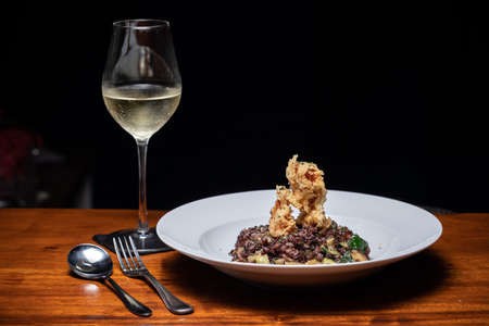 Traditional Spanish seafood paella on a dark wooden table with white wine Veganの写真素材
