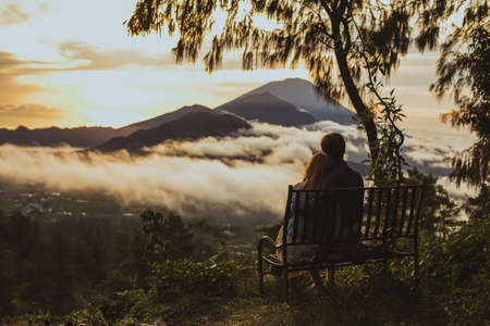 A loving couple, a man and a woman sitting near Batur volcano. Sunrise, sunsetの写真素材