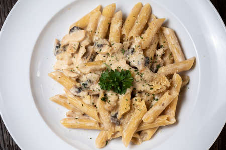 Penne pasta with white mushrooms porcini in creamy sauce on the dark wood tableの写真素材