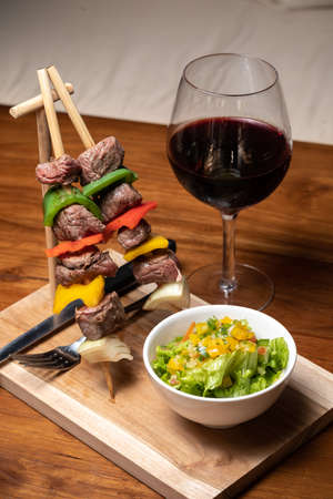 Meat beef kebab with vegetables and spices, red wine. Dark wood table.の写真素材