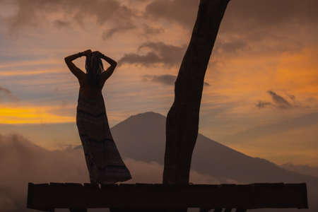 Girl in a long dress stands with Bali landmark volcano Agung view. Sunsetの写真素材