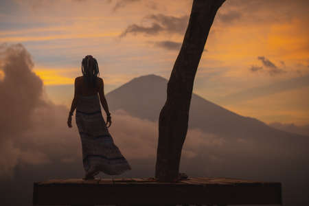 Girl in a long dress stands with Bali landmark volcano Agung view. Sunsetの写真素材
