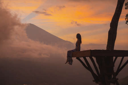 Girl in a long dress stands with Bali landmark volcano Agung view. Sunsetの写真素材