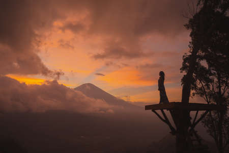 Girl in a long dress stands with Bali landmark volcano Agung view. Sunsetの写真素材