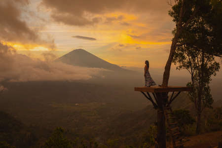 Girl in a long dress stands with Bali landmark volcano Agung view. Sunsetの写真素材