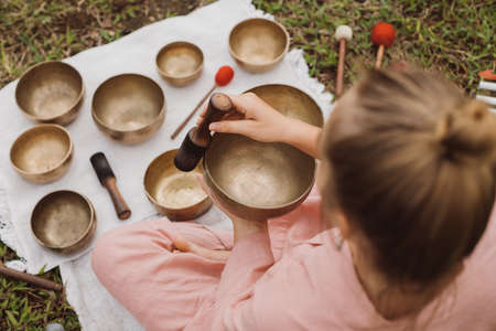 Young woman with white hair in a pink kimono plays on a singing bowlの写真素材