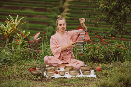 Blonde woman in a pink kimono playing on meditative Himalayan Tibetan musicの写真素材
