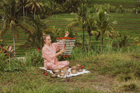 Blonde woman in a pink kimono playing on meditative Himalayan Tibetan musicの写真素材