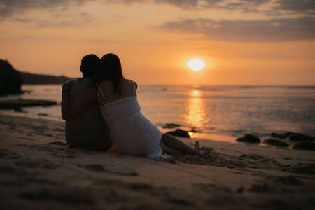 Honeymoon romantic couple in love sitting on the Maldives beach at sunsetの写真素材