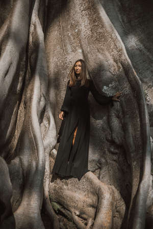 Brunette with long hair posing in a 700 years old Banyan tree. Bali, Indonesiaの写真素材