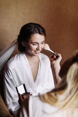 Beautiful happy smile bride with wedding makeup and hairstyle in bedroom, newlywed woman final preparation for wedding. Marriage Wedding day moment.の写真素材