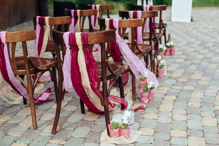 Wedding chairs with tapes,wedding ceremony in outside.rustik style. White door arch in green tree backgroundの写真素材