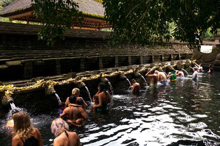 Balinese people praying in holy spring water of sacred pool at Pura Tirta Empul Temple, Tampaksiring, BALI, INDONESIA - 2 April 2018.のeditorial素材