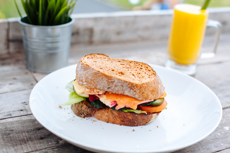 Healthy Breakfast with Wholemeal Bread toast and salmon, vegetables, cheese and fruit mango juice on the wooden background.の写真素材