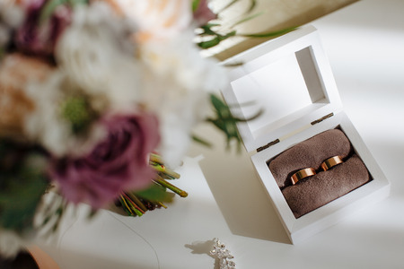 wedding golden wide rings in wooden box and bouquet with beautiful roses. Preparation.の写真素材