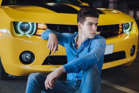 fashion portrait of handsome man sitting near the modern yellow sport car. Fashion. Modern. Advertisingの写真素材