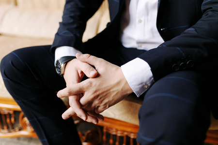 Man sitting with his hands crossed. Mens hand in a blue suit, watch on the mans hand, the hand of a businessman, , hands of a man close-up. Groom wedding.の写真素材