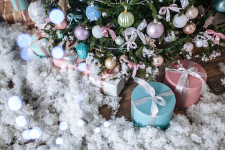 Christmas gifts packed with pink, paper and tapes under decorated tree. Copy space.の写真素材