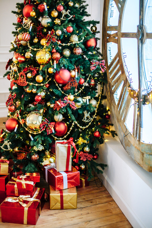 Christmas Gifts wrapped in classic red paper, background with xmas lights bokeh of blurred under Christmas tree. Copy space.の写真素材
