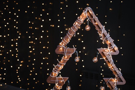 Alternative wooden christmas tree. A handmade New Year tree with light bulb on garland lights black...