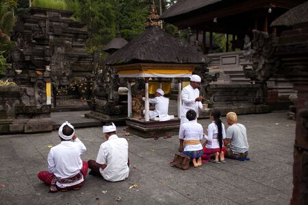 SEPTEMBER 18, 2014 - BALI, INDONESIA: Hindu devotees pray at the Tirta Empul Temple led by a high priest. Hinduism is the religion of the majority of the Balineseのeditorial素材
