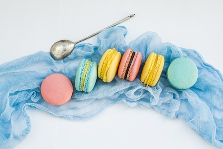 Sweet colorful French macaroon biscuits on blue pastel textile background, top view. Flay lay selection of macaronsの写真素材