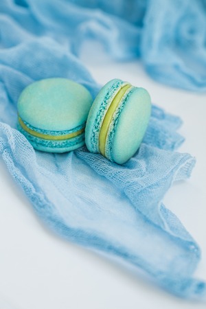 pistachio French macaroon biscuits on blue pastel textile background, top view. Flay lay selection...