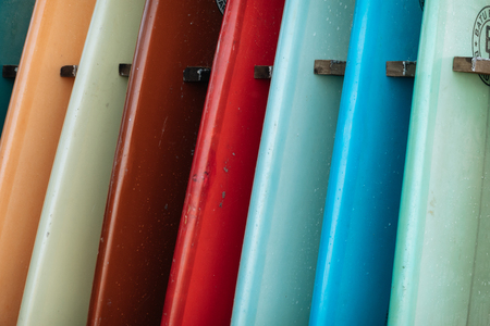 Close up Set of different color surf boards in a stack by ocean.の写真素材