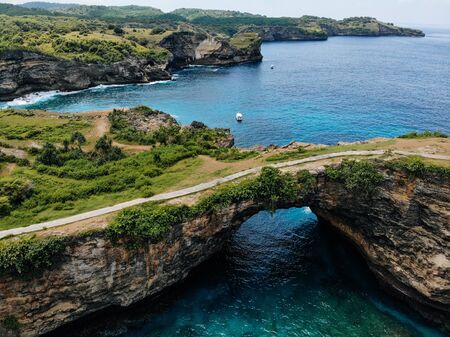 Rock coastline Stone arch over the sea. Broken beach Nusa Penida Indonesia. Drone photoの写真素材