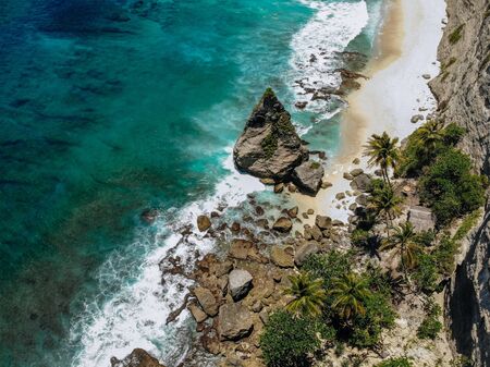 Aerial drone photo of tropical beach, sea rocks, turquoise ocean and palm trees. Atuh beach, Nusa...
