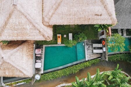 Aerial view of luxury hotel with straw roof villas and pools in tropical jungle and palm trees. Luxurious villa, pavilion in forest, Ubud, Baliの写真素材