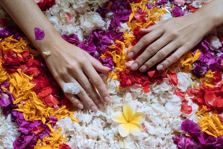 Top view female hands on flowers petals in bath tub in luxury bathroom in hotel. Hands close up, spa weekend, wellbeing, body care and beauty treatment conceptの写真素材